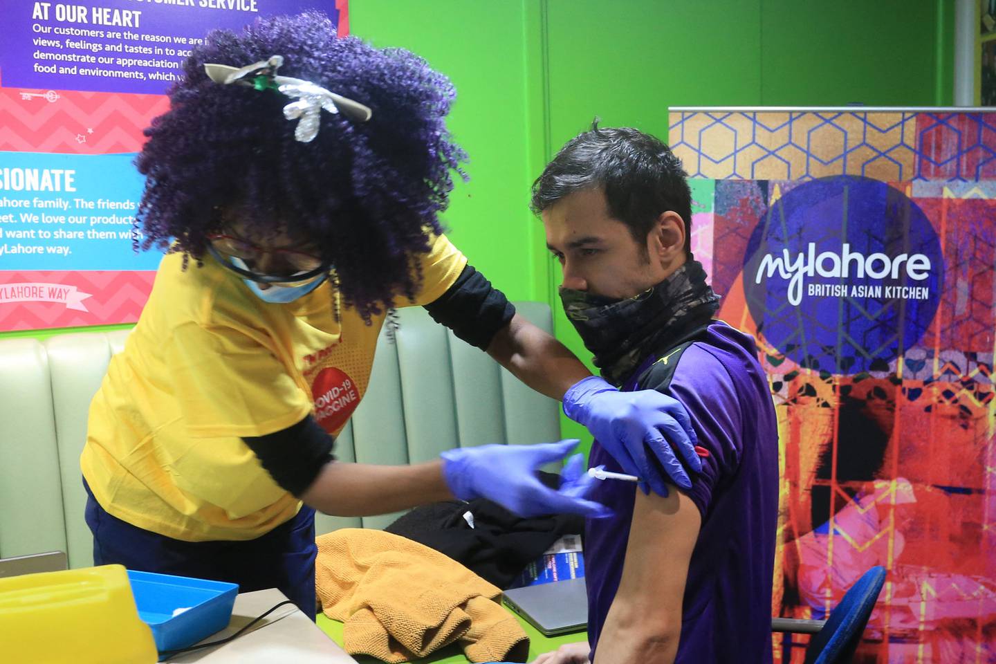 A health worker gives a man a Covid booster jab at a pop-up vaccination centre at the MyLahore British Asian Kitchen in Bradford, West Yorkshire.  AFP