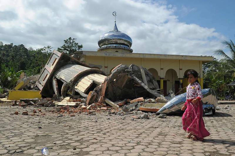 An Acehnese girl walks past a collapsed mosque minater following an earthquake in Pidie, Aceh province on December 7. Chaideer Mahyuddin / AFP 