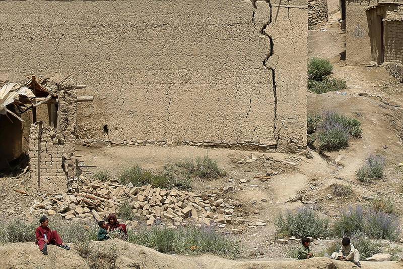 Afghan children play in the backdrop of houses damaged after the earthquake. AFP