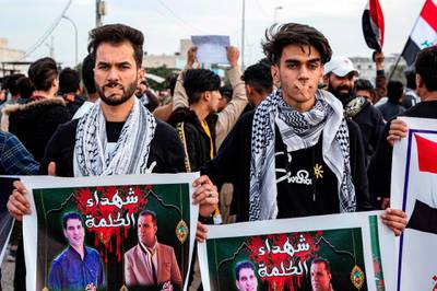 Protesters wearing bandages crossing their mouths stand holding up signs showing the faces of two slain journalists captioned in Arabic "martyrs of the word" during an anti-government demonstration, also calling for freedom of the press, in the southern Iraqi city of Basra.  AFP