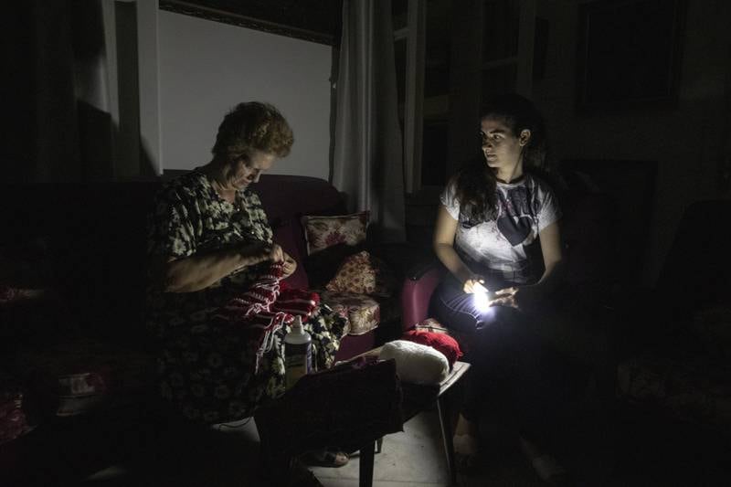 A resident knits by torchlight in an apartment during a power cut at night in Beirut in September. Bloomberg