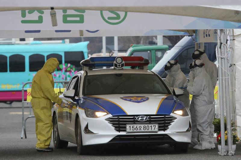Medical staff wearing protective suits take samples from a driver with symptoms of the coronavirus at a "drive-through" virus test facility in Goyang. AP