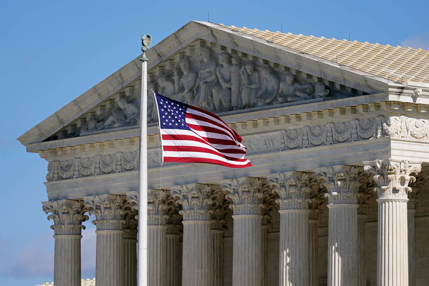 FILE - In this Nov. 2, 2020, file photo an American flag waves in front of the Supreme Court building on Capitol Hill in Washington. The Supreme Court is hearing arguments over whether the Trump administration can exclude people in the country illegally from the count used for divvying up congressional seats. (AP Photo/Patrick Semansky, File)