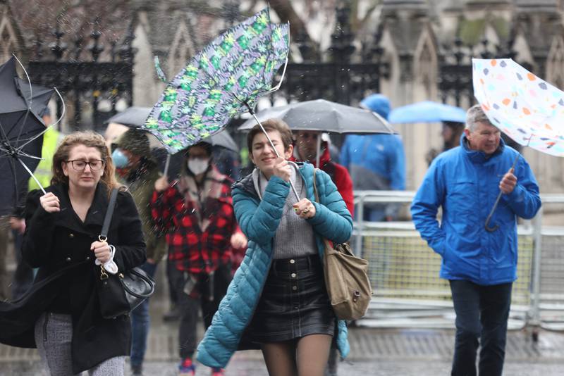 Members of the public brace against the wind and wet weather in Westminster, central London. AP
