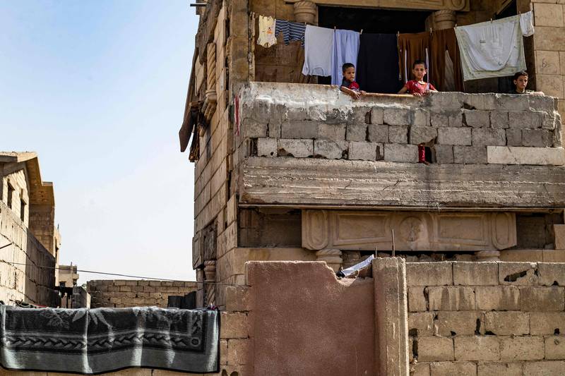 Syrian children, displaced with their family from Deir Ezzor, stand on the balcony of a damaged building where they are living in Syria's northern city of Raqqa.