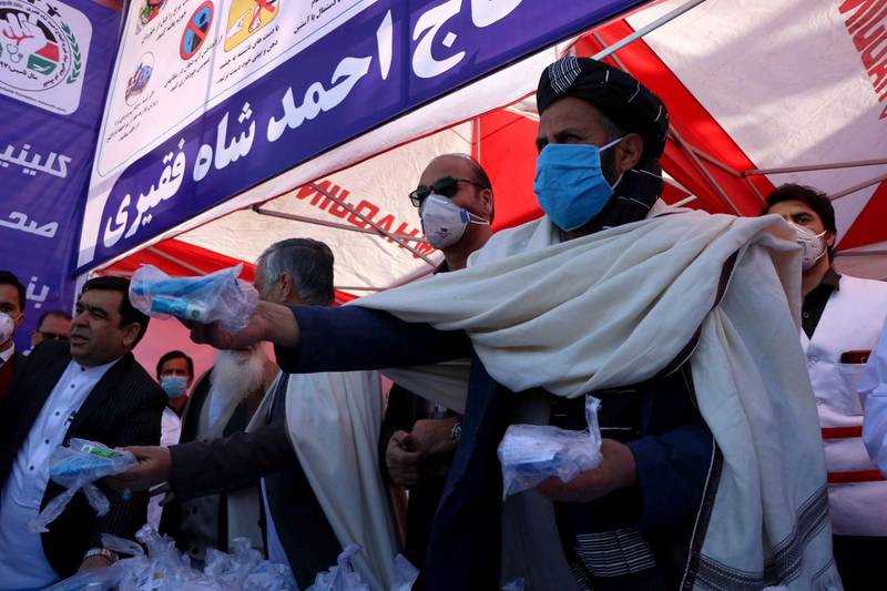 Afghans distribute free masks on a road after positive cases of Coronavirus near the Iranian border in Herat, Afghanistan.  EPA