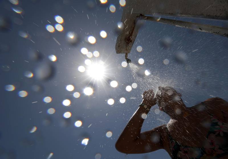 A woman stands under a shower on the beach in Nice as a heatwave hits much of the country, France, June 28, 2019.  REUTERS/Eric Gaillard