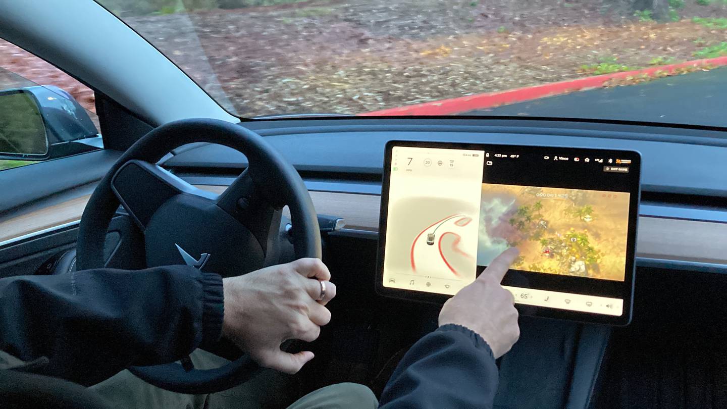 A new Tesla owner demonstrates on a closed course in Portland, Oregon, how he can play video games while driving, on December 8, 2021. The US has opened an investigation into a report that Tesla vehicles allow people to play video games on a centre touch screen while behind the wheel. AP 