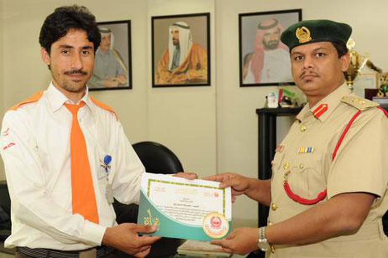 Omar Hayah Ajmal Khan, left, receives a certificate from Dubai Police after returning about Dh120,000 worth of Saudi Riyals he found left in the back of his taxi.