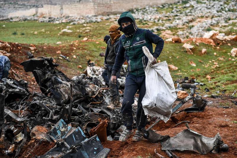 Syrians gather around the wreckage of a government military helicopter that was shot down Friday, in the countryside outside Idlib, Syria, Saturday, Feb. 15, 2020.AP
