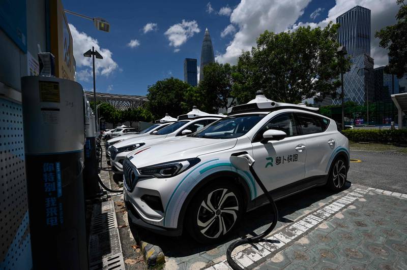 Apollo Go robotaxis charging at a station in Shenzhen. Chinese driving regulations do not currently allow autonomous vehicles on the road without a steering wheel. Manual override is required for safety reasons. AFP