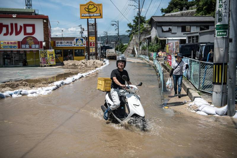 HIROSHIMA, JAPAN - JULY 10: A man rides a scooter along a flooded road following a landslide, on July 10, 2018 in Yanohigashi near Hiroshima, Japan. Over 112 people have died and 78 are missing following floods and landslides triggered by "historic" levels of heavy rain across central and western parts of Japan while more than 73,000 rescuers are racing to find survivors as temperatures rise. Japan's Prime Minister Shinzo Abe warned on Sunday of a "race against time" to rescue flood victims as almost 2 million people are subject to evacuation orders and tens of thousands remain without electricity and water. (Photo by Carl Court/Getty Images)