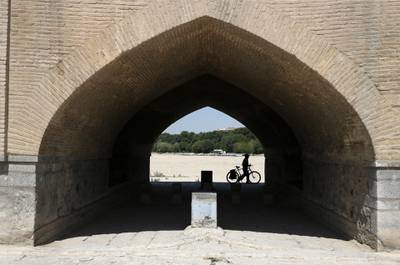 A man walks his bicycle under the Si-o-seh Pol bridge in Isfahan, July 10, 2018. AP Photo