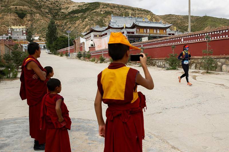 Tibetan Buddhist monks wave to a participant at the trail of the Super Salmon ultra-marathon near the Longyangxia Reservoir in Gonghe County, Qinghai province, China, August 11, 2018.  Picture taken August 11, 2018.  REUTERS/Thomas Peter