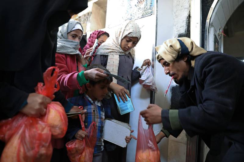 A woman and children receive food donations from a charity kitchen in Sanaa, Yemen January 14, 2021. REUTERS/Khaled Abdullah