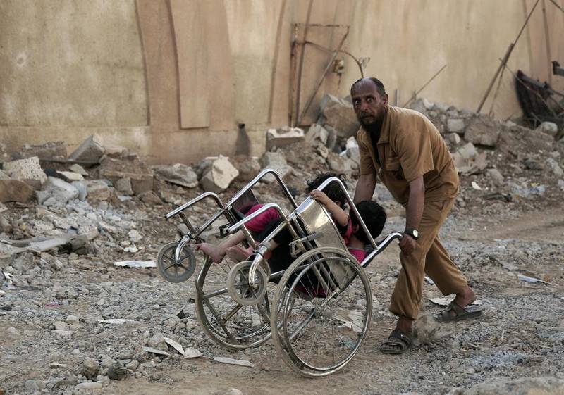 A terrified man pushes two children in a wheelchair as they flee heavy fighting between ISIL militants and Iraqi special forces in Mosul, Iraq on May 10, 2017. Maya Alleruzzo/AP Photo