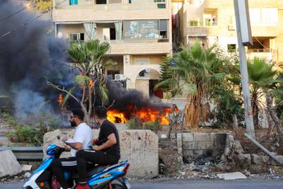 Men drive past a vehicle following clashes in the Khalde area, south of Beirut.