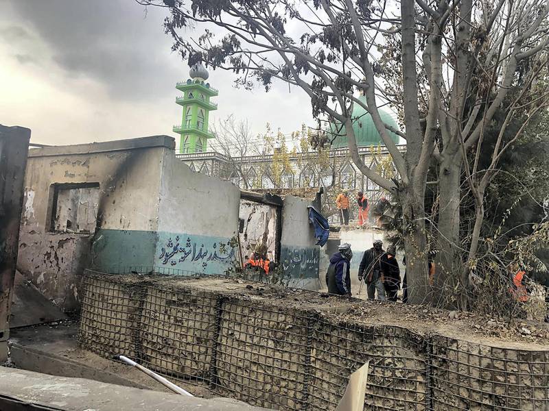 Volunteers and workers clean up debris and damage from two days of protests in western Kabul on November 27, 2018. Hikmat Noori for The National