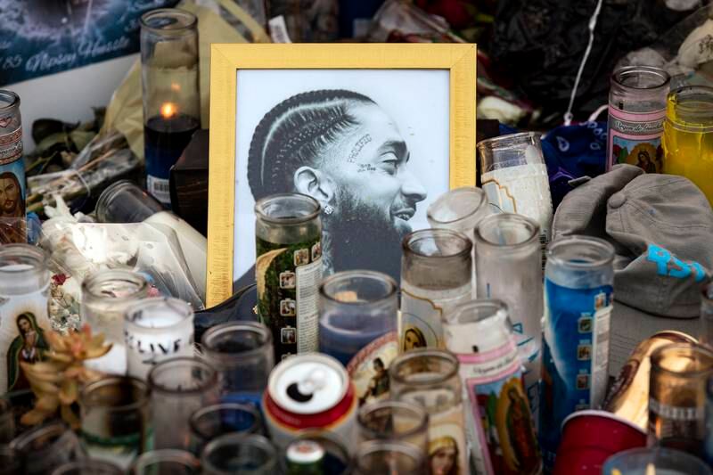 epa07481586 Candles and portraits of US rapper Nipsey Hussle sit on the ground where he was shot in Los Angeles, California, USA, 02 April 2019. On 01 April 2019, as people came to pay their respects to Nipsey Hussle, a sudden stampede injured several people, some seriously. Thirty-three-year-old US rapper Nipsey Hussle was shot dead on March 31, in a parking lot in front of his clothing shop. Nipsey Hussle's killing was among the 11 murders within the past week alone in Los Angeles.  EPA/ETIENNE LAURENT