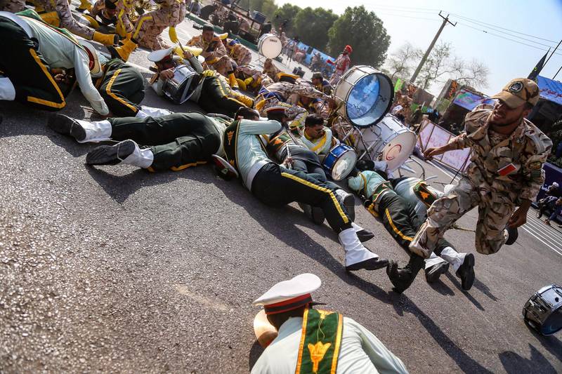 This picture taken on September 22, 2018 in the southwestern Iranian city of Ahvaz shows a soldier running past injured comrades lying on the ground at the scene of an attack on a military parade that was marking the anniversary of the outbreak of its devastating 1980-1988 war with Saddam Hussein's Iraq. Dozens of people were killed with dozens others wounded in an attack in the southwestern Khuzestan province on September 22 targeting on an army parade commemorating the anniversary of the 1980-1988 Iran Iraq war, state media reported. / AFP / ISNA / MORTEZA JABERIAN
