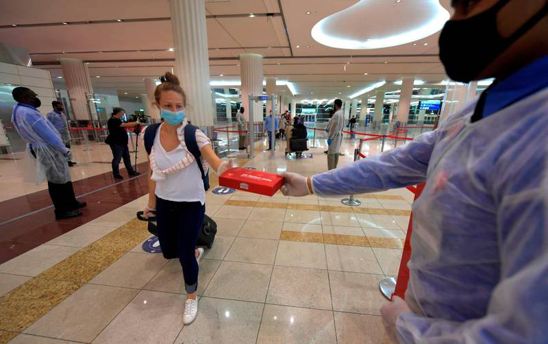 A passenger of an Emirates airlines flight departing to the Australian city of Sydney, receives a box of masks and gloves at Dubai International Airport, after the resumption of scheduled operations by the Emirati carrier, amid the coronavirus pandemic crisis. AFP