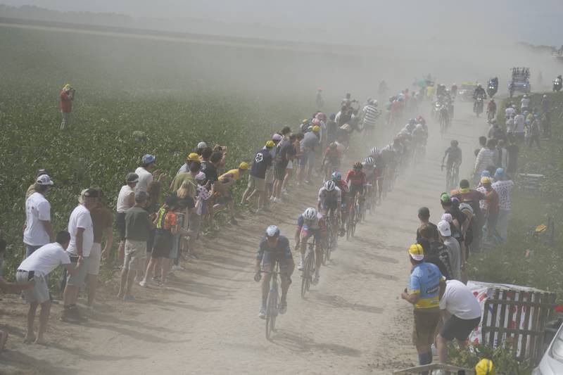 The peloton kicks up dust as it rides over the cobblestones during Stage 5. AP