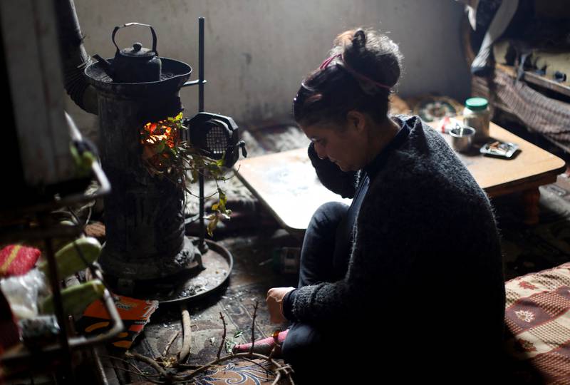 Ahlam Warda, a single mother raising three children, sits next to a wood-fire heater at her home in Damascus, Syria. All photos: Reuters