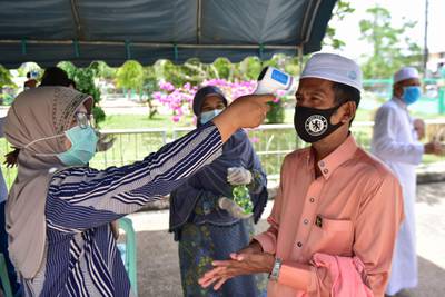 A public health officer checks the temperature of a Muslim man as he arrives to attend Friday prayers at a mosque in the southern Thai province of Narathiwat as restrictions aimed at curbing the spread of the COVID-19 novel coronavirus are slowly eased.   AFP