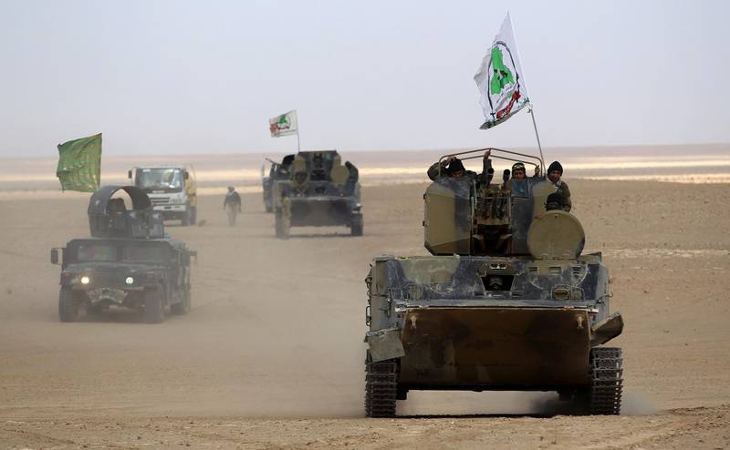 An infantry fighting vehicle (IFV) flying the flag of Asa'ib Ahl al-Haq, one of the units of the Hashed al-Shaabi (Popular Mobilisation units), advances with the Iraqi forces through Anbar province, 20 kilometres east of the city of Rawah in the western desert bordering Syria, on November 25, 2017, in a bid to flush out remaining Islamic State (IS) group fighters in the al-Jazeera region. / AFP PHOTO / AHMAD AL-RUBAYE