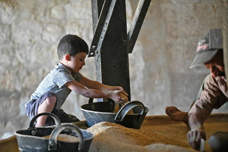 A child helps as Syrian Kurdish men work with a wheat mill said to be 100 years old. All photos: AFP