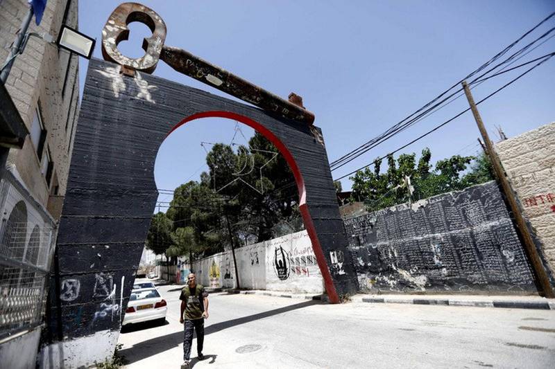 epa07580617 A Palestinian walks near by street artwork believed to have been created by street artist Banksy, in Aida refugee camp in the West Bank city of Bethlehem 18 April 2019. The Palestinian key is a widely used symbol of the 'Nakba' the  Palestinian exodus, as many Palestinians kept the keys to their homes in 1948 In Waiting for the Return.  Banksy is an anonymous England-based street artist, well known by his graffiti anti-Israel.  EPA-EFE/ABED AL HASHLAMOUN *** Local Caption *** 55202731