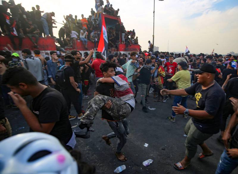 Iraqi demonstrators evacuate an injured protester from the scene of clashes with security forces on Al-Jumhouri Bridge in the capital Baghdad, following a demonstration to mark the first anniversary of a massive anti-government movement demanding the ouster of the entire ruling class accused of corruption.  AFP