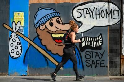 A member of the public makes their way past some graffiti on Sauchiehall Street in Glasgow, which encourages people to 'stay home'. Getty Images