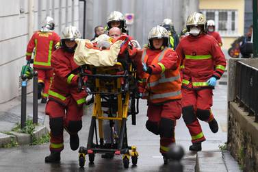 French firefighters push a trolley carrying an injured man near the former offices of the French satirical magazine Charlie Hebdo. AFP