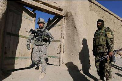A US soldier and an Afghan National Army soldier leave a house during a patrol in a village in Ghazni province.