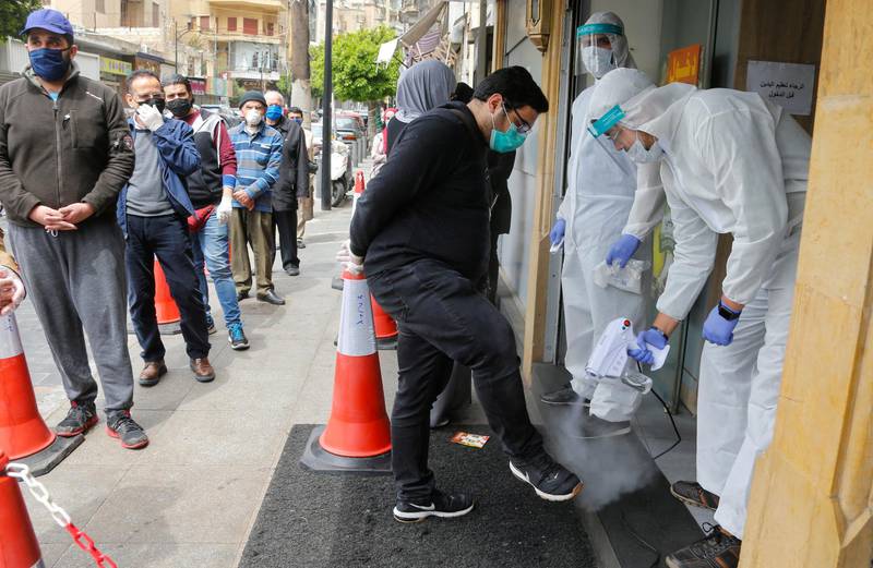 Workers wearing protective gear spray disinfectant on customers before entering a supermarket, during a lockdown to prevent the spread of coronavirus in Beirut, Lebanon. Reuters