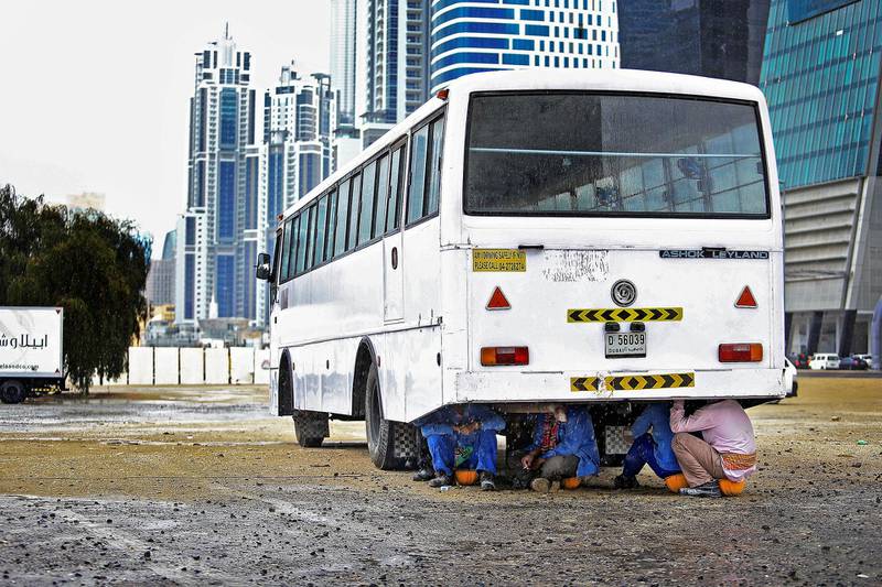 DUBAI, UAE. January 7, 2014 - Construction workers seek shelter from the rain under a bus in Dubai, January 7, 2014.  (Photo by: Sarah Dea/The National, Story by: STANDALONE, News)