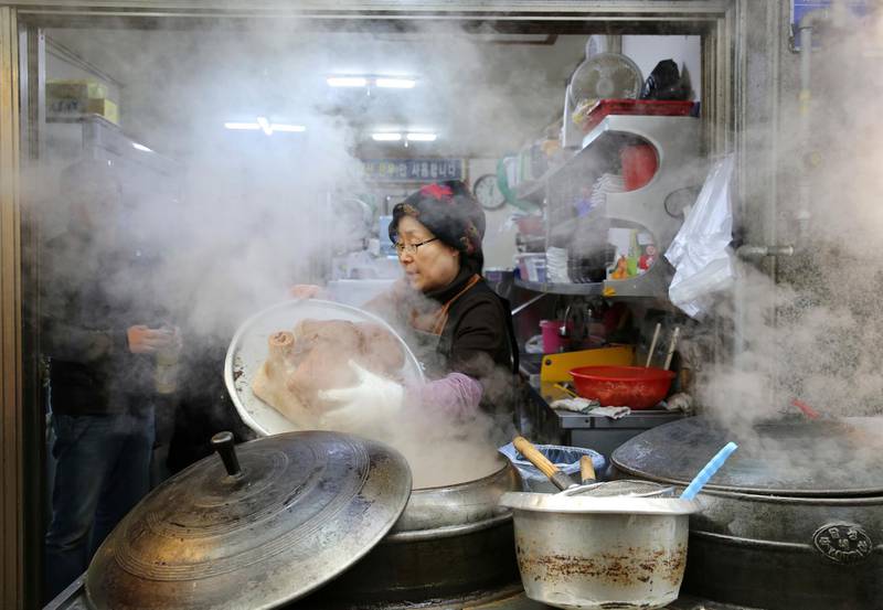 A woman cooks an Ox head outside her restaurant at a market in Gangneung, South Korea. Gangneung is one of the venues of the 2018 Winter Olympics. Aaron Favila / AP Photo
