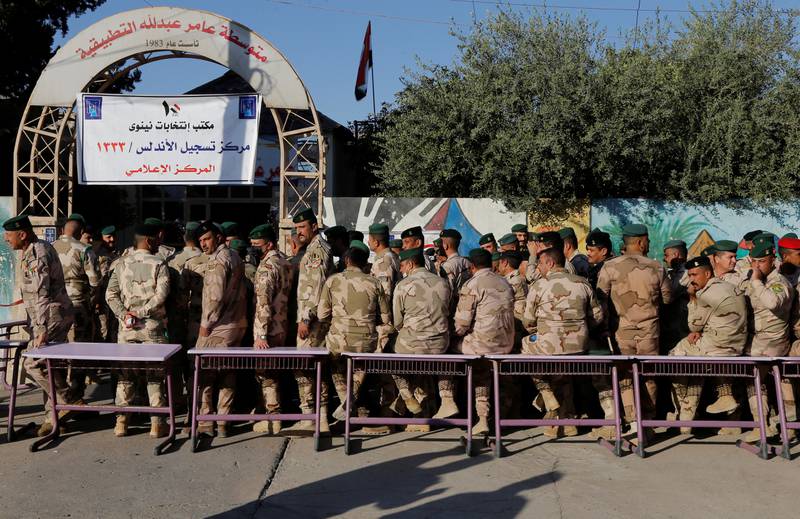 Members of Iraqi security forces outside a polling station in Mosul wait to cast their vote. Reuters