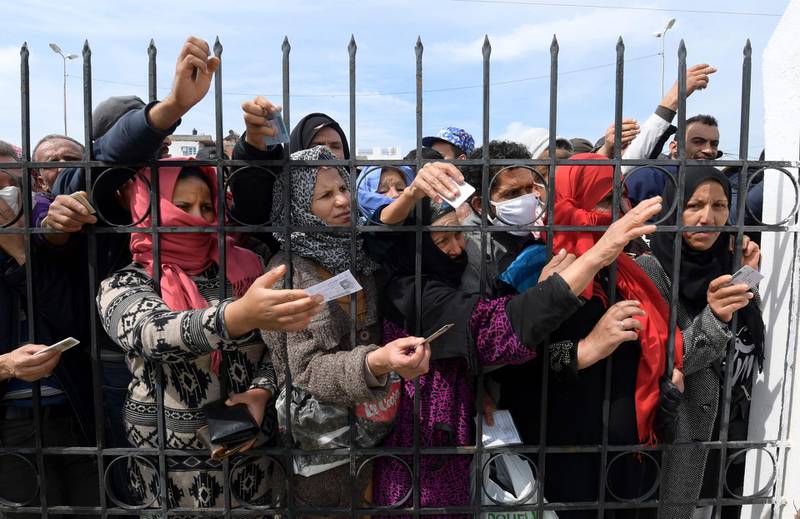 Impoverished Tunisian citizens gather with their identification cards in front of the headquarters of Mnihla delegation in Ariana Governorate outside Tunis on March 30, 2020, to protest against the general confinement and to claim the financial aid promised by the government.  / AFP / FETHI BELAID
