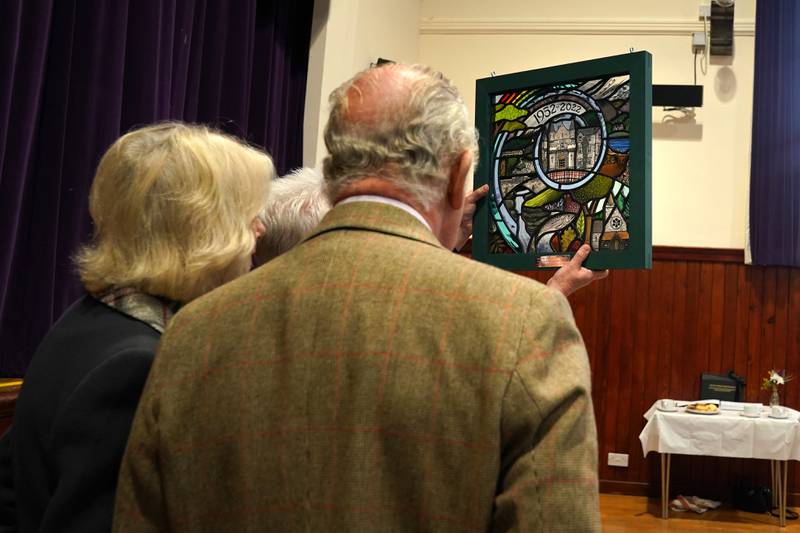 King Charles and the Queen Consort view a piece of stained glass at the Victoria & Albert Halls in Ballater. PA