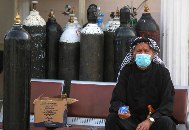 An Iraqi man waits next to oxygen bottles for his wife who is a patient with COVID-19 at the Ibn Al-Khatib Hospital in Baghdad, on April 25, 2021, after a fire erupted in the medical facility reserved for the most severe coronavirus cases. - At least 23 people died when a fire broke out in a coronavirus intensive care unit in the capital of Iraq, a country with long-dilapidated health infrastructure facing mounting COVID-19 cases. (Photo by AHMAD AL-RUBAYE / AFP)