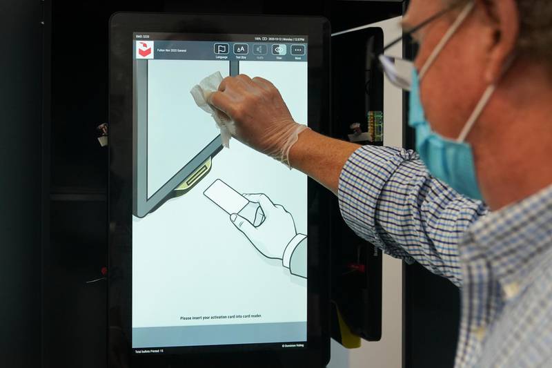 A poll worker sanitizes a voting machine screen at an early voting polling location for the 2020 Presidential election in Atlanta, Georgia, U.S. Bloomberg