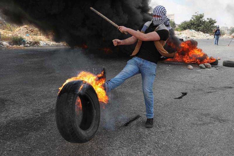 A Palestinian protester kicks a burning tyre during a demonstration near the Jewish settlement of Beit El in the occupied West Bank, following the reported death of Bassam Al Sayeh in an Israeli prison. AFP
