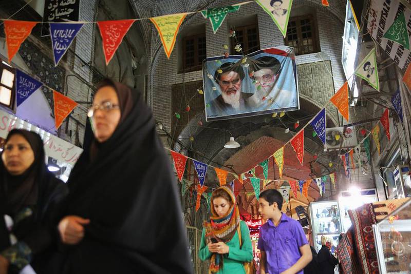 Portraits of  the late Ayatollah Khomeini, left, and Iran’s current supreme leader Ayatollah Khamenei hang over shoppers in the historic Bazar-e Bozorg in Isfahan.