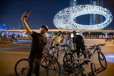 Riders take selfies in front of Museum of the Future. 