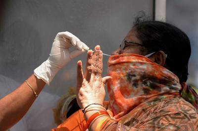 A woman reacts as a health worker prepares to collect a nasal swab sample to test for the Covid-19 coronavirus at primary health centre, in Hyderabad. AFP