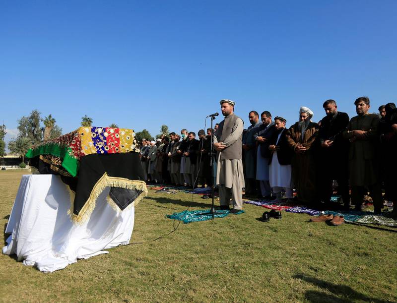 Afghan men pray near the coffin of journalist Malalai Maiwand, who was shot and killed by unknown gunmen in Jalalabad, Afghanistan December 10, 2020. REUTERS/Parwiz