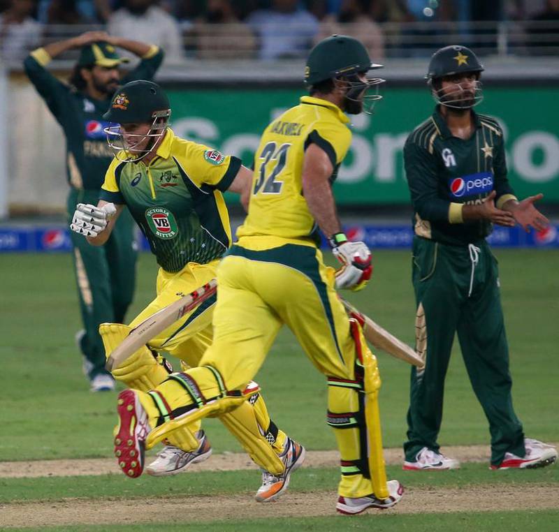 Australian batsmen Glenn Maxwell, right, and George Bailey run between wickets during the second One Day International (ODI) cricket match against Pakistan in Dubai on October 10, 2014. AFP PHOTO/ MARWAN NAAMANI