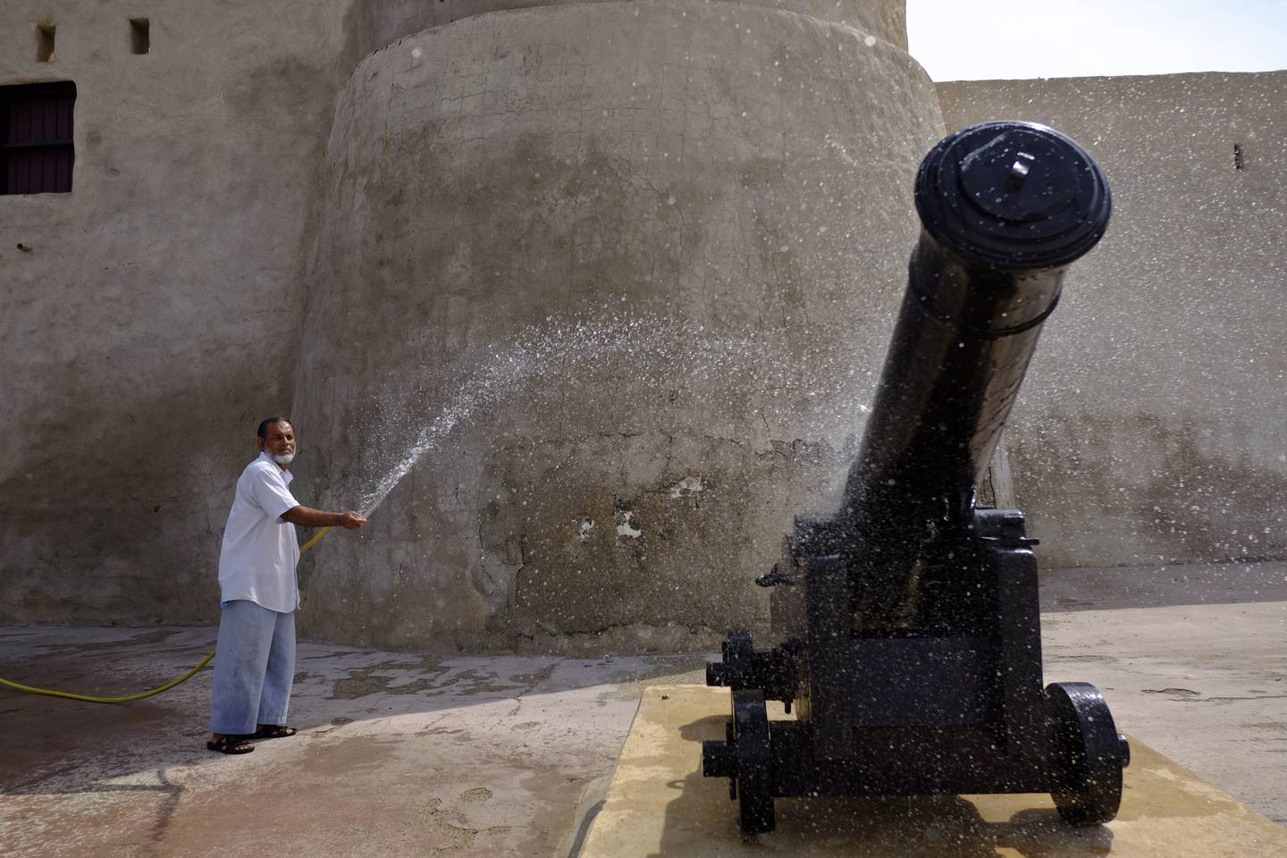 UMM AL QUWAIN, UNITED ARAB EMIRATES, MARCH 10, 2014. Mohammed Nazeen (Bangladesh) washes dust from the canon displayed in the Umm Al Quwain Museum.  The fortress from 1768, which originally served as the Emiri residence, was fully restored and opened to the public in 2000.  (Photo: Antonie Robertson / The National) Journalist: Jen Bell.  Section: Northern Reporting POSSIBLE FOCAL POINT